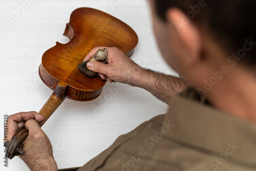 Close-up of unrecognizable Latin American Luthier varnishes a violin the old fashioned way using natural dyes. Concept stringed instruments