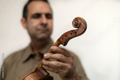 Latin American luthier holds an unfinished violin in his hands, selective focus on the violin. Concept stringed instruments