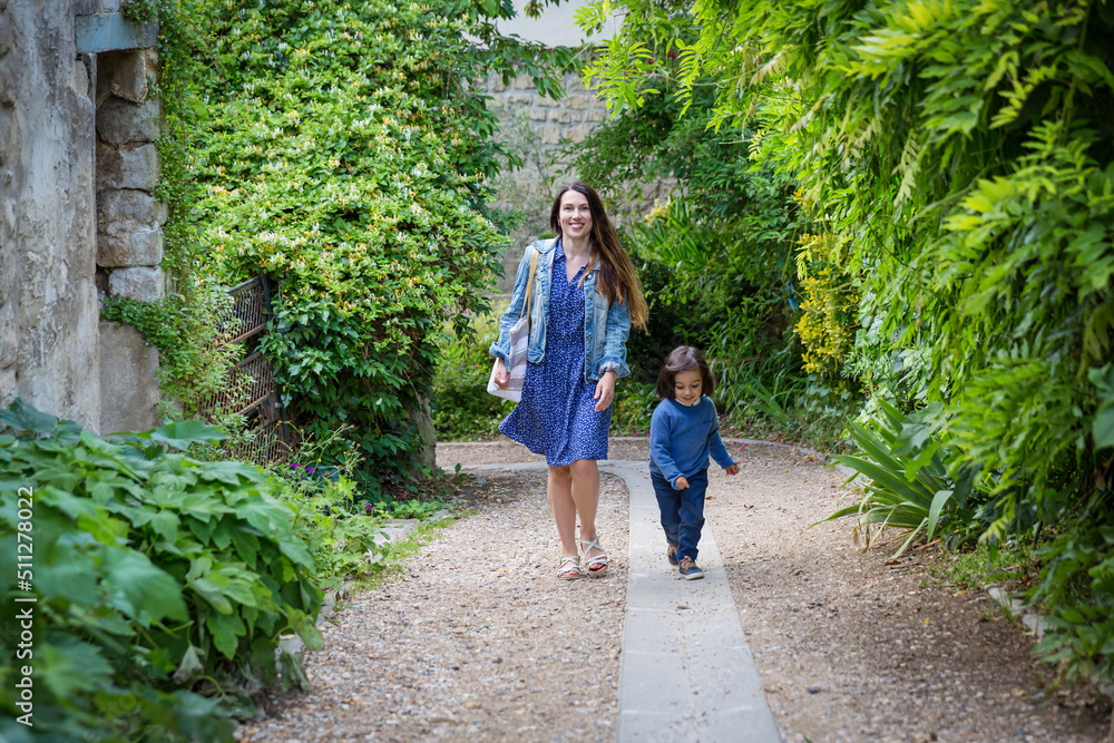 Mother and little handsome baby boy walking outdoor in old city park. Happy family spending time together