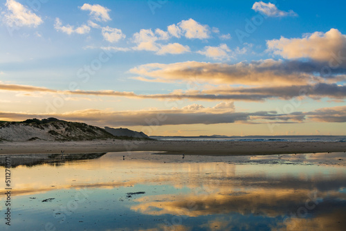 Picturesque clouds reflected in shallow waters of a sandy beach. Beautiful sunset at Far North  New Zealand