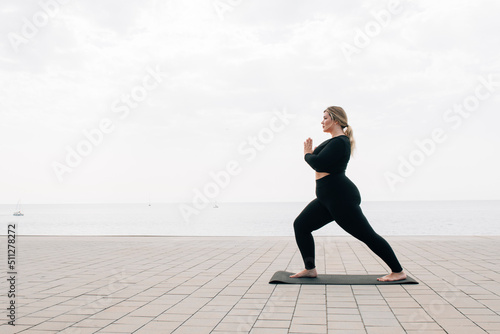 plus size girl practicing yoga in front of the ocean