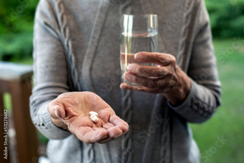 close-up of older woman holding pills and glass of water