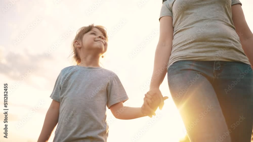 mother daughter walking in the park. happy family kid dream concept. close-up daughter holding her mother hand walking along the road in the park in nature. sun mom daughter outdoors in the park mother daughter walking in the park. happy family kid dream concept. close-up daughter holding her mother hand walking along the road in the park in nature. sun mom daughter outdoors in the park