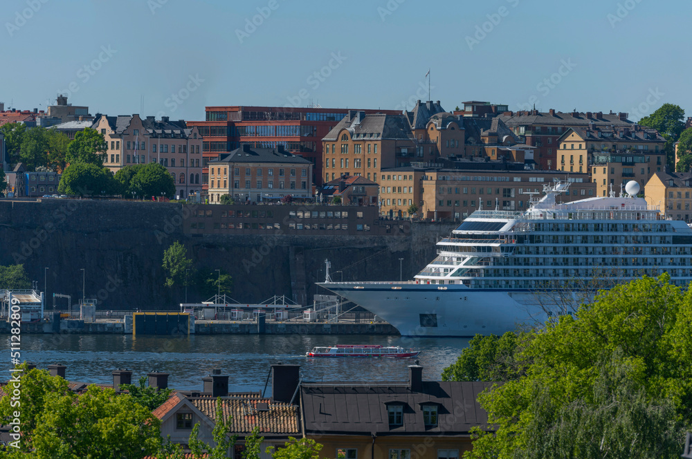 Obraz premium Vista point view with black tin roofs, cruise ship in the lake Saltsjön and old and new apartment houses in the district Södermalm a sunny summer day in Stockholm