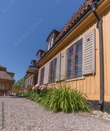 Façade of a yellow wood mansion building with dorms and flowers in a park a sunny summer day in Stockholm