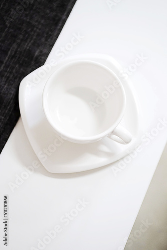 Empty white tea cup and saucer on the table. Porcelain dishes, selective focus.