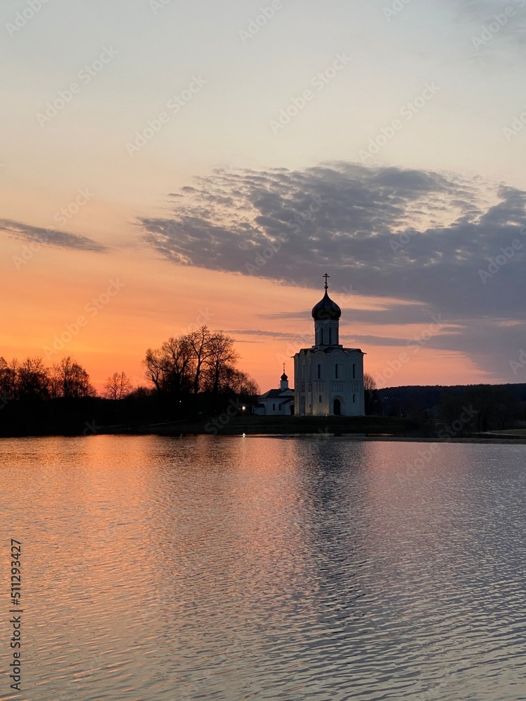 The ancient Church of the Intercession on the Nerl in the bright hour of dawn - during the flood, when the overflowing water flooded the trees, the meadow and the path to the church.