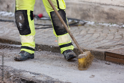 Worker in reflective clothing sweeping street