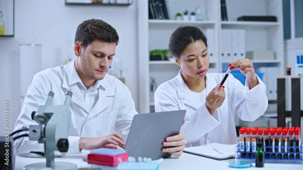 Diagnostic laboratory workers checking blood samples, inserting data on laptop Diagnostic laboratory workers checking blood samples, inserting data on laptop