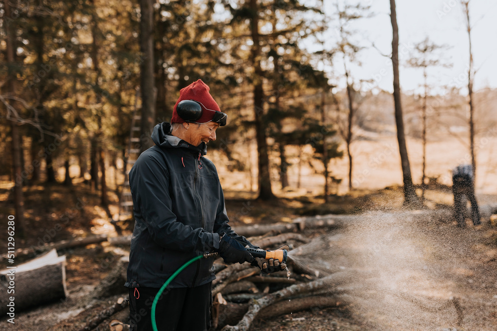 Woman using water hose in forest Woman using water hose in forest