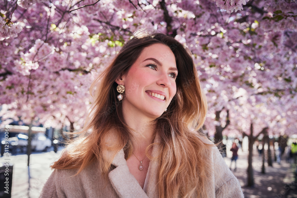 Young woman standing under cherry blossom Young woman standing under cherry blossom