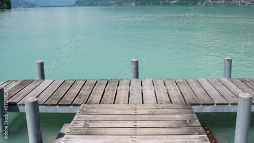 Beautiful view from the wooden pier to the lake on a sunny summer day, Brienz lake with clear turquoise water. Brienz lake in the village of Iseltwald, Switzerland