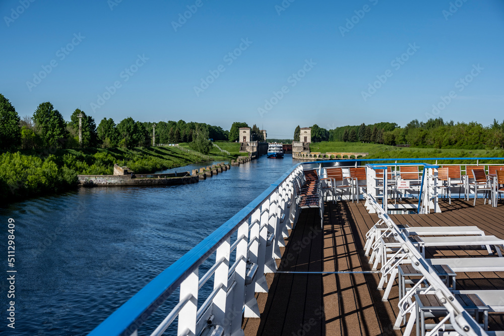 river boat passes through the lock on the river on a summer day