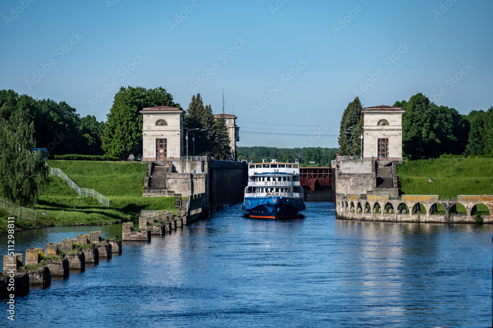 river boat passes through the lock on the river on a summer day