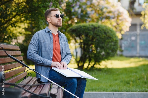 Blind man reading book on bench in park