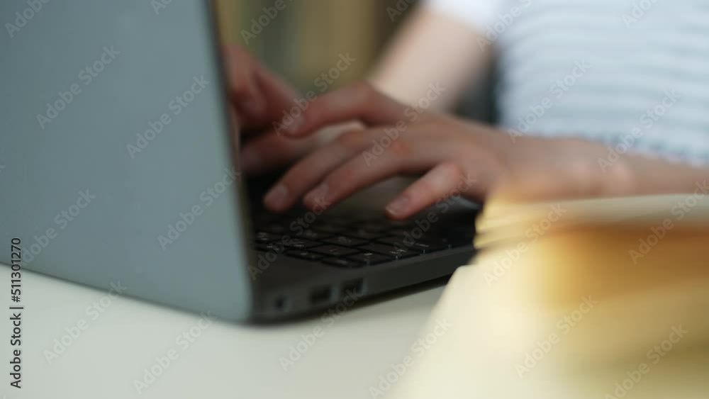 Close-up tracking shot of unrecognizable child school girl typing on laptop keyboard, learning distantly at home, doing home task sitting at table. Pupil schoolgirl e-learning online using computer. Close-up tracking shot of unrecognizable child school girl typing on laptop keyboard, learning distantly at home, doing home task sitting at table. Pupil schoolgirl e-learning online using computer.
