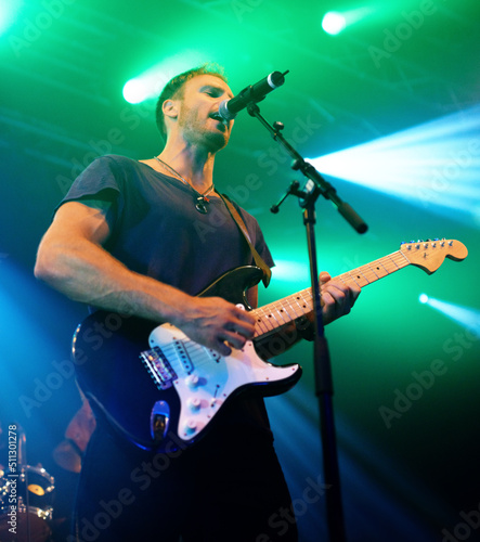 In the glorious moment. Attractive musician playing his guitar at a concert.