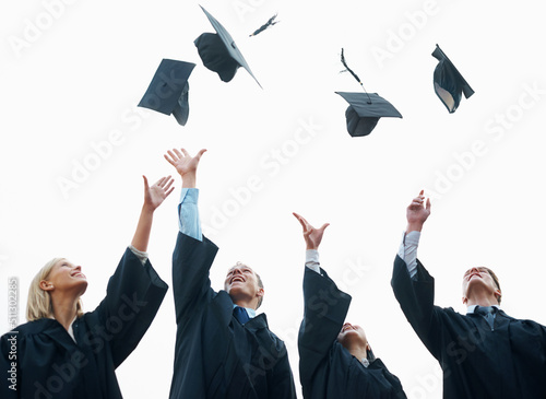Celebrating the start of their adult lives. A group of students throwing their caps into the air after graduation.