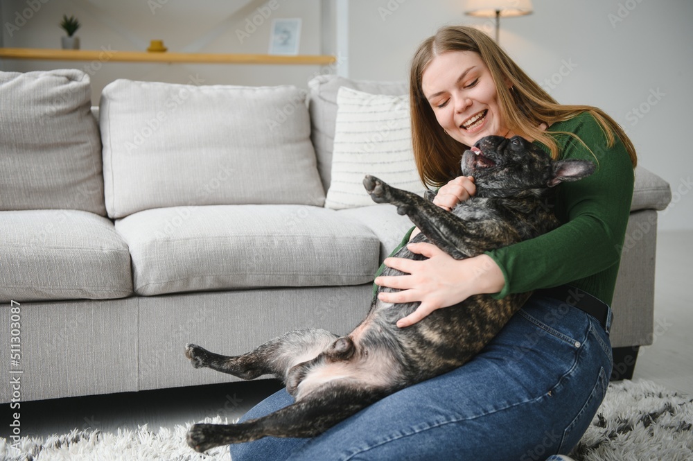 Obraz premium beautiful girl, smiling and sitting on floor near French bulldog