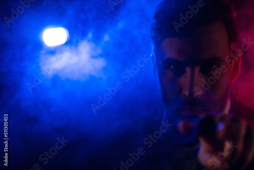 Close up photo of male face and blue light on the background.