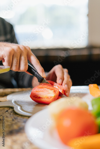 Vertical medium shot photo of a man's hands chopping vegetables for lunch