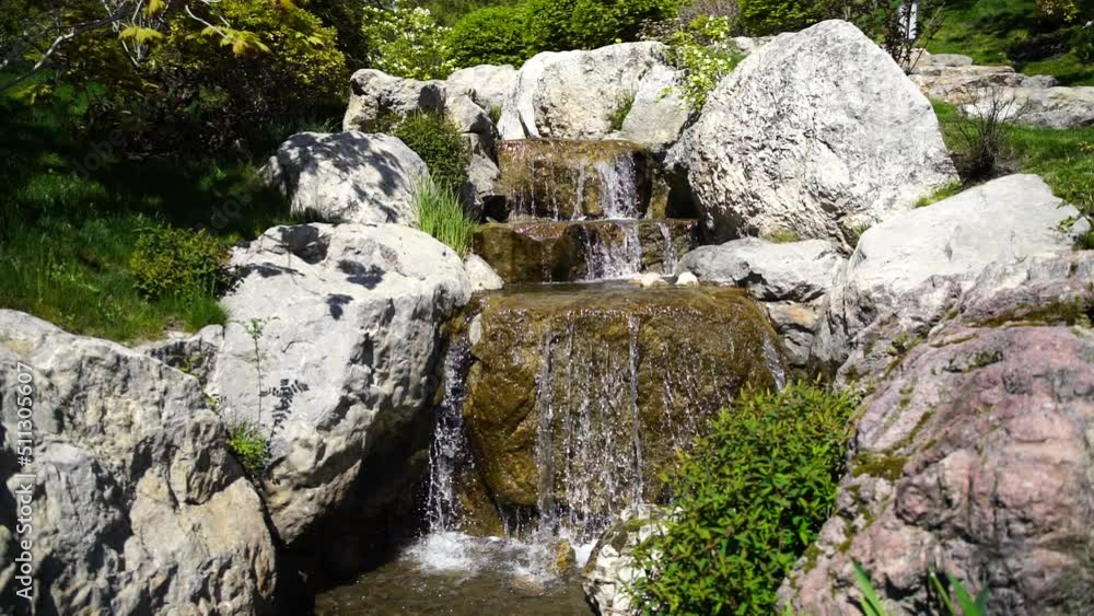 Waterfall in a Japanese garden, water slowly flows over large stones of volcanic origin Waterfall in a Japanese garden, water slowly flows over large stones of volcanic origin