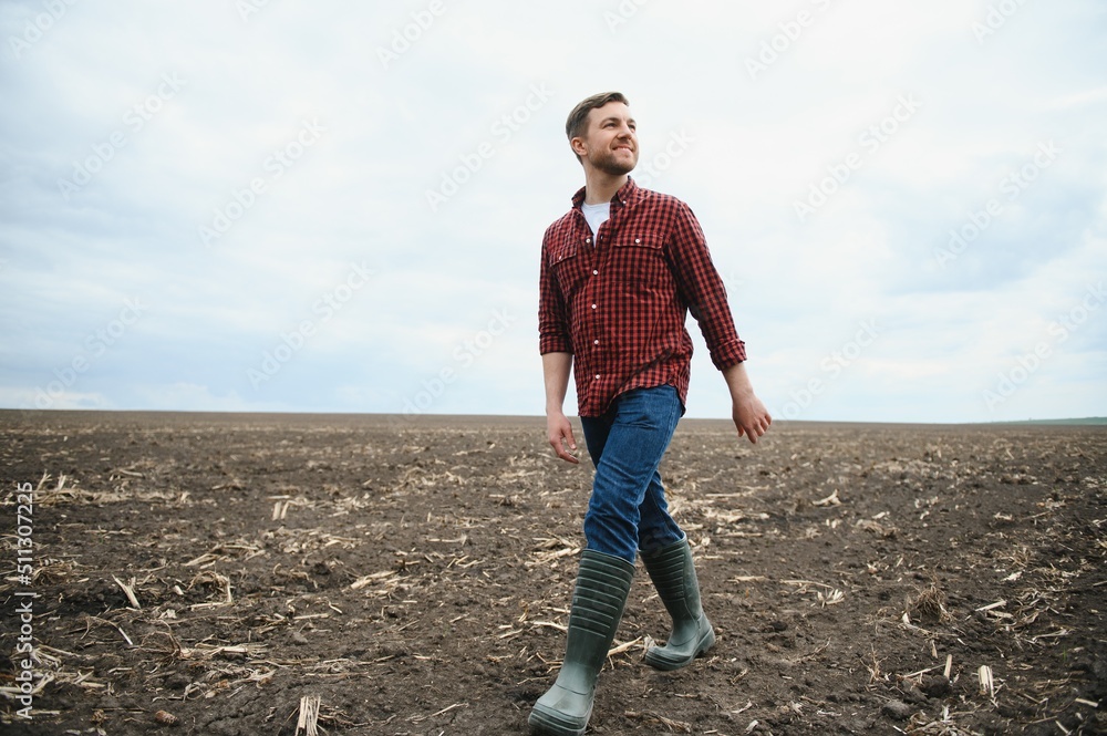 A farmer in boots works with his tablet in a field sown in spring. An agronomist walks the earth, assessing a plowed field in autumn. Agriculture. Smart farming technologies A farmer in boots works with his tablet in a field sown in spring. An agronomist walks the earth, assessing a plowed field in autumn. Agriculture. Smart farming technologies