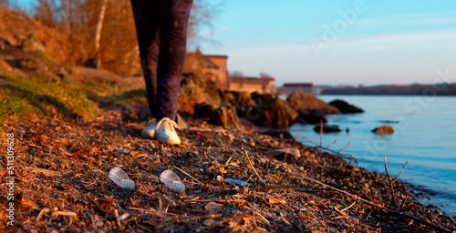 trash plastic cup, microplastics on the seashore in the evening at sunset