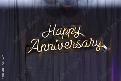 neon sign board reading happy anniversary isolated in white background
