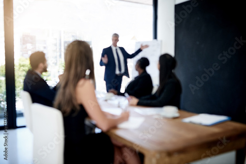 Hes got their undivided attention. Defocused shot of a team of businesspeople attending a presentation in the boardroom.