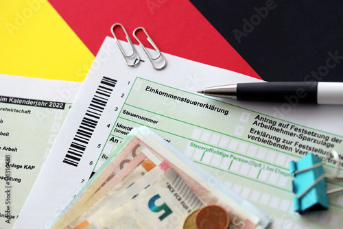 German income tax return form with pen and european euro money bills lies on flag close up. Taxpayers in Germany using euro currency to pay taxes photo