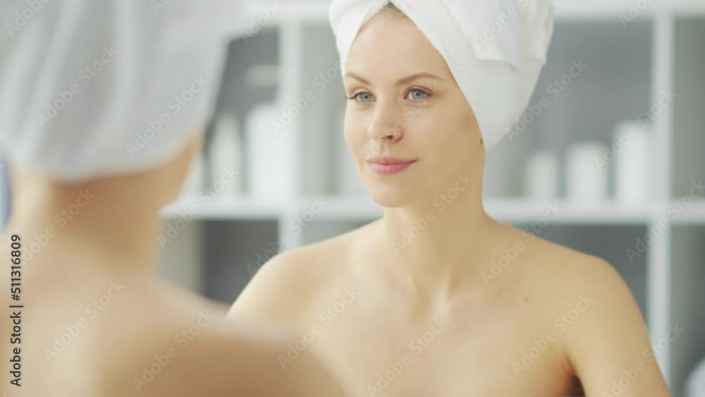 Young Girl is Sitting in front of a Make-up Mirror in the Bathroom and Applying a Skin Cream. Beautiful Woman is Making Cosmetic Rejuvenation Procedures. Health and Beauty Concept. Young Girl is Sitting in front of a Make-up Mirror in the Bathroom and Applying a Skin Cream. Beautiful Woman is Making Cosmetic Rejuvenation Procedures. Health and Beauty Concept.