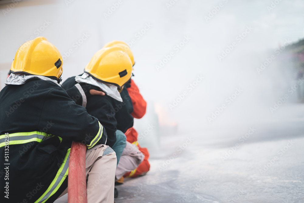 In to the fire,Brave firefighter using extinguisher and water from hose for fire fighting, Firefighters training, foreground is drop of water springer.. In to the fire,Brave firefighter using extinguisher and water from hose for fire fighting, Firefighters training, foreground is drop of water springer..