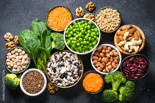 Vegan protein source  healthy nutrition food. Legumes  beans  nuts  vegetables and seeds. Top view on black stone table.
