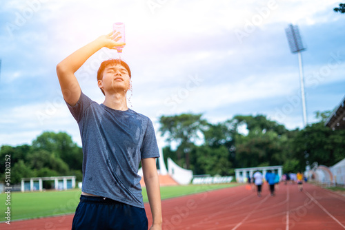 Fitness man splashing water in face cooling down from bottle splashing water after running workout in park.