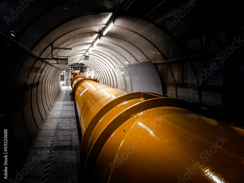 Illuminated gas or oil, orange pipeline in dark tunnel.