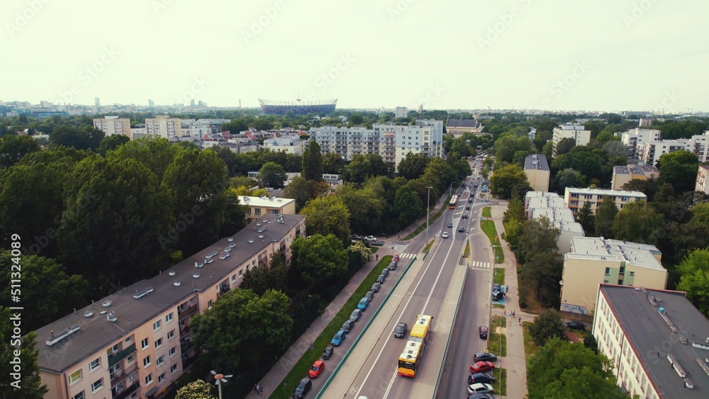 Aerial view of a street in suburbs of a big modern city with low-rise buildings, cars, buses and green tall trees. High quality photo