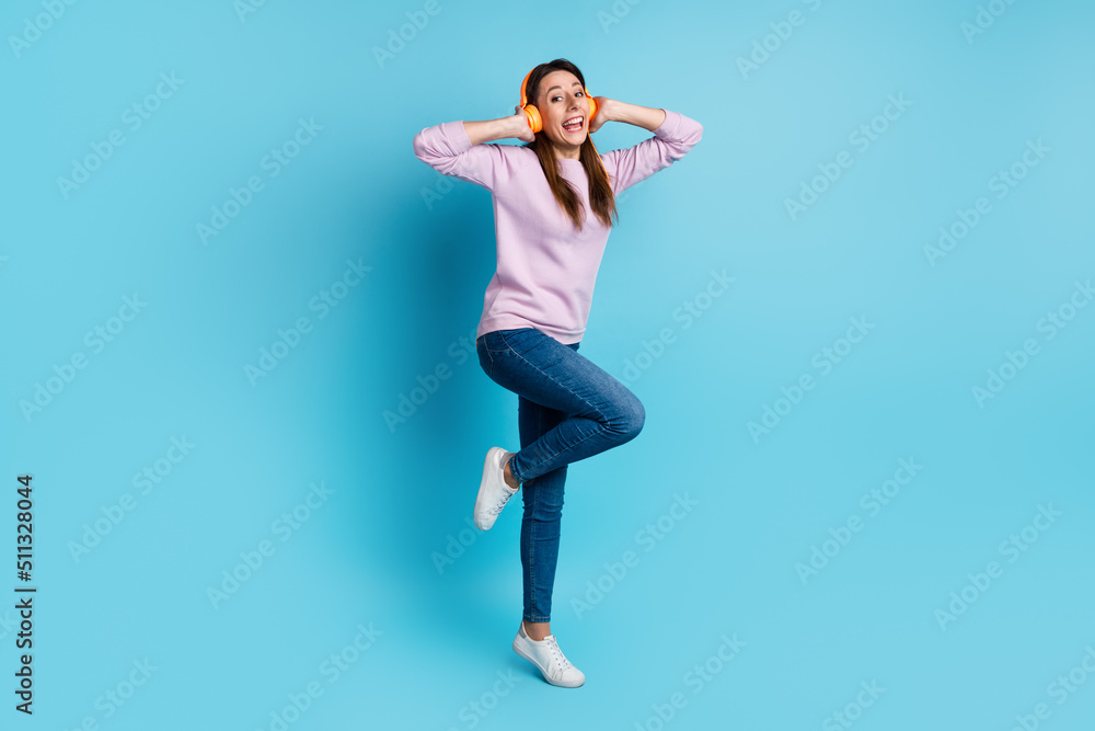 Full size photo of young excited woman have fun listen music headphones isolated over blue color background Full size photo of young excited woman have fun listen music headphones isolated over blue color background