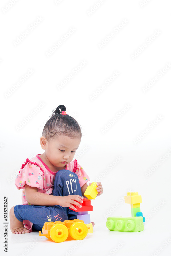 Lovely little cute asian girl playing on the floor with lots of colorful plastic blocks in studio, isolated on white background Lovely little cute asian girl playing on the floor with lots of colorful plastic blocks in studio, isolated on white background