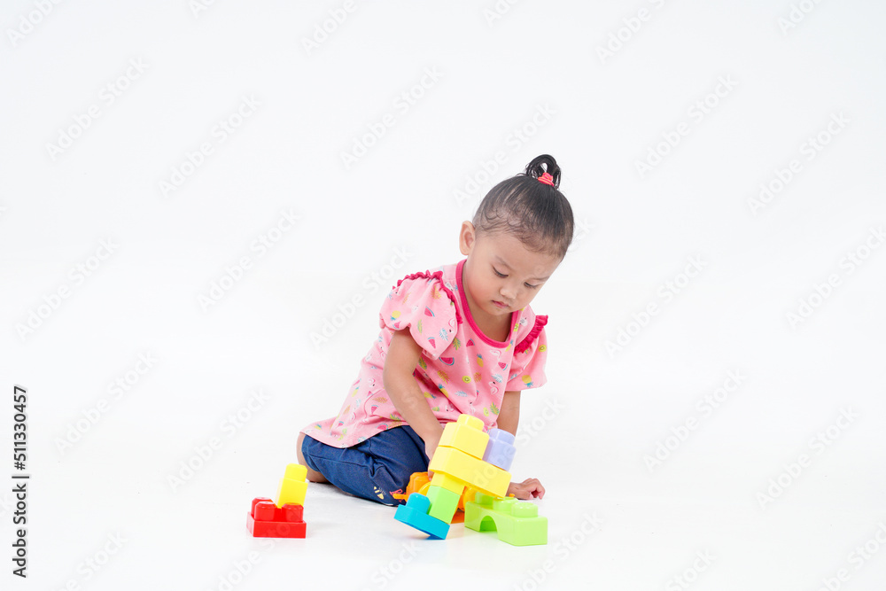 Lovely little cute asian girl playing on the floor with lots of colorful plastic blocks in studio, isolated on white background Lovely little cute asian girl playing on the floor with lots of colorful plastic blocks in studio, isolated on white background