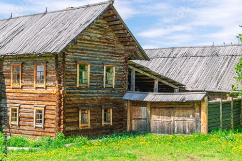 Wallpaper Mural A two-storey old house in the village made of dark logs with a wooden roof. Summer flowers in front of the house in the countryside. Wooden old manor house of the 19th century Torontodigital.ca