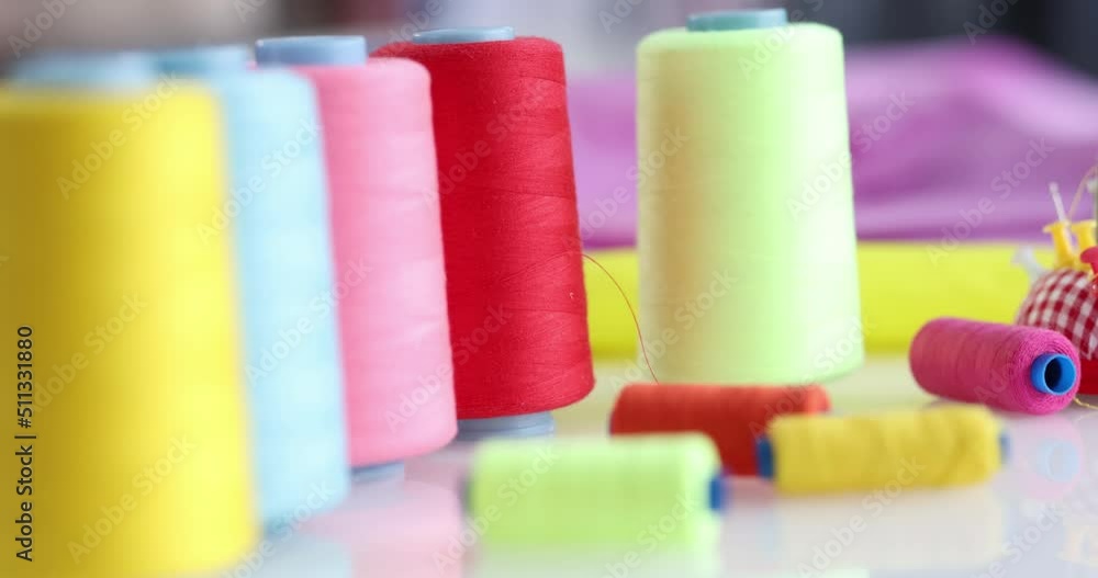 Colored spools of thread on the table, slow motion Colored spools of thread on the table, slow motion