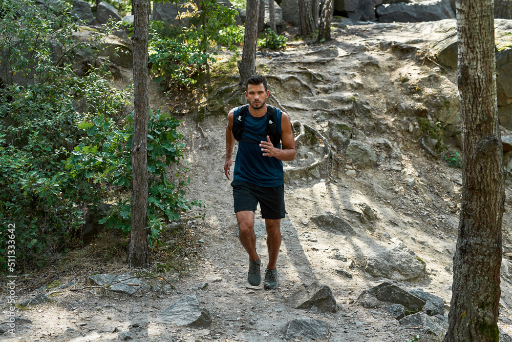 Young caucasian sportsman jog up on hill in forest Young caucasian sportsman jog up on hill in forest