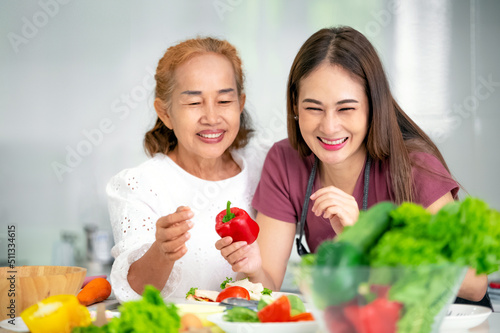 mother and daughter cooking in the kitchen, mother and daughter hugging to love on mother's day, Asian family