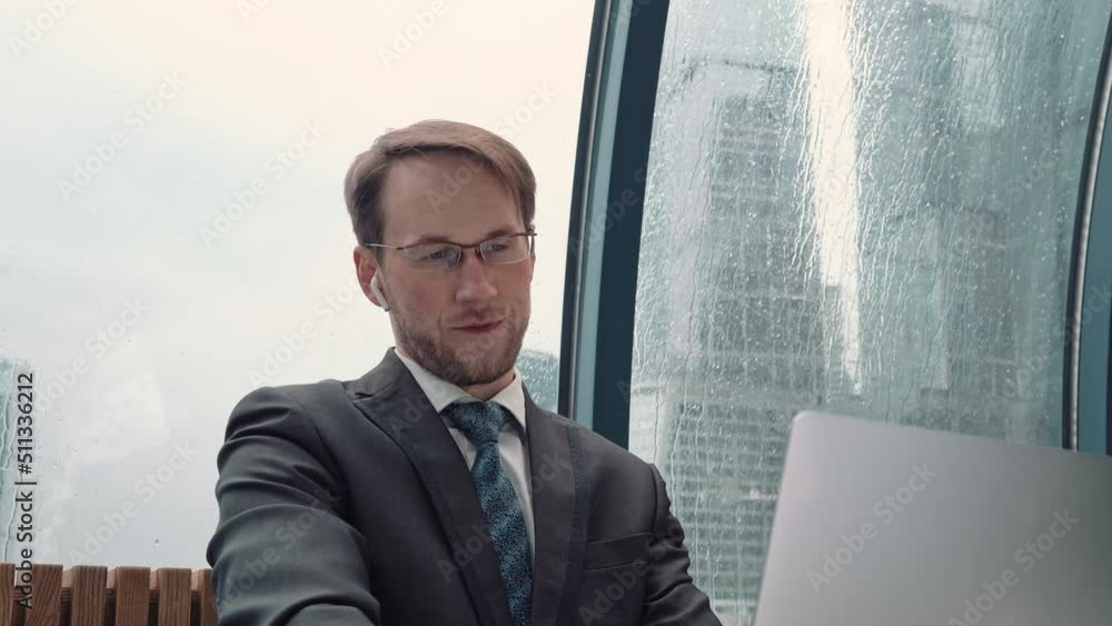 Businessman talking on a video conference call, online communication, working process, rainy and cloudy outside. Businessman talking on a video conference call, online communication, working process, rainy and cloudy outside.
