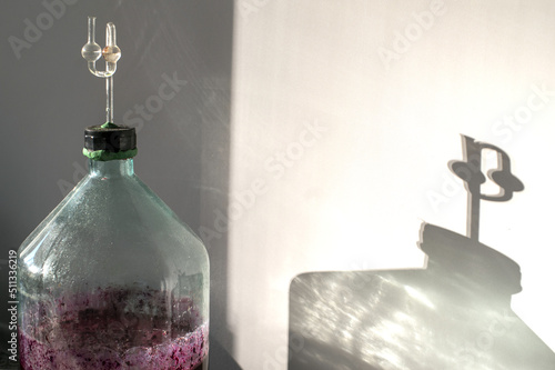 The process of making red homemade wine. A glass bottle with a must with an airlock in a cork. Selective focus.