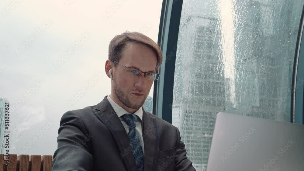 Businessman talking on a video conference call, online communication, working process, rainy and cloudy outside. Businessman talking on a video conference call, online communication, working process, rainy and cloudy outside.