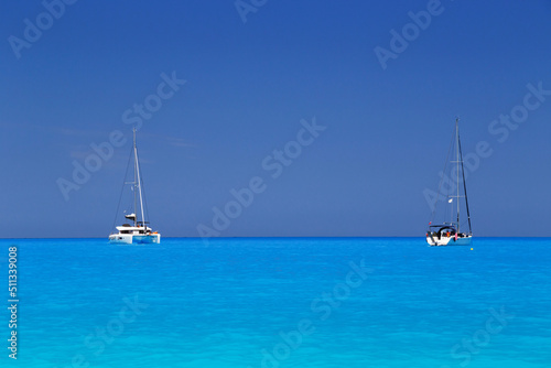 White yachts anchored in fantastic Myrtos Beach turquoise and blue bay. Summer scenery of famous and extremely popular travel destination in Cephalonia island, Greece, Europe.