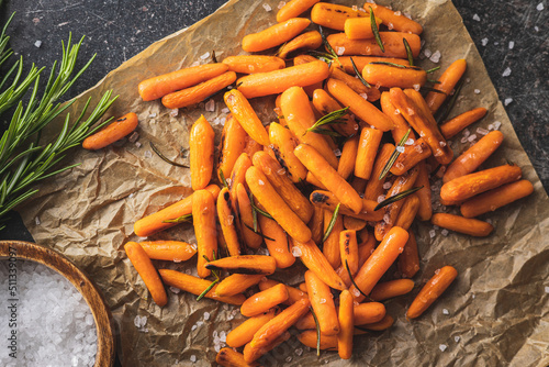 Roasted baby carrots with salt and rosemary on baking paper. photo