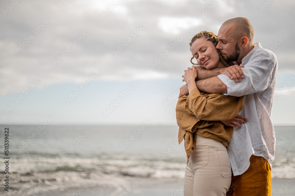 Young loving couple standing and hugging on a beach